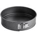 A round black metal springform cake pan with a metal handle.