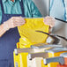 A man in a blue shirt using a yellow Heinz mustard bag to refill a dispenser.