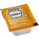 A Heinz honey portion cup on a white surface.