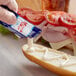 a person pouring mayonnaise on a sandwich