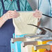 A man in a blue apron using a Heinz Ranch dressing pouch to dispense dressing.