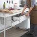 A person opening a Regency stainless steel drawer set in a professional kitchen.