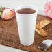 A white Dart ThermoGuard paper hot cup filled with tea sits on a table with cookies.