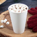 A Dart white paper hot cup of hot chocolate with marshmallows and a red fuzzy glove.