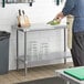 A person cutting vegetables on a Regency stainless steel work table with undershelf.