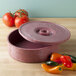 A red HS Inc. tortilla server with a lid next to tomatoes.