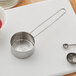 An American Metalcraft stainless steel measuring cup with wire handle on a cutting board.