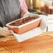 A woman holding a loaf of bread in a white Novacart loaf mold.