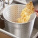 A hand pouring pasta from a colander into a pot.