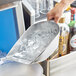 A person holding the Choice aluminum flat bottom scoop filled with ice cubes.