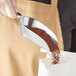 A hand using a Choice flat bottom aluminum scoop to pour coffee into a bag.