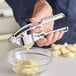 A person using a Choice Chrome Garlic Press to squeeze garlic into a bowl.