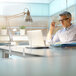 A man sitting at a desk with a MasterVision glass safety shield clamped to it.