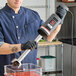 A Sammic XM-51 heavy-duty 16-inch variable speed immersion blender being used in a commercial kitchen.