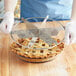 A person holding a metal pie with a Choice stainless steel pie cutter.