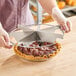 A person using a Choice stainless steel pie cutter to cut a pie.