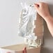 A hand putting a plastic bag of Noble Chemical Novo Pro Series foaming hand sanitizer into a dispenser.