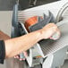 A person using a Hobart meat slicer to cut meat.