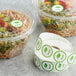 A Point Plus roll of green vegan food labeling stickers on a table with containers of food.