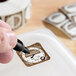 A dissolvable Thursday day of the week clock label being marked on a food container.