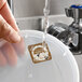 A dissolvable day of the week clock label marked 'Thursday' adhered to a plastic container lid under running water.
