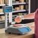 A person weighing meat on an AvaWeigh digital price computing scale with a tower.