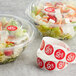A salad in a plastic container with a red Point Plus label next to a roll of Point Plus red labels.