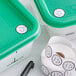 A green and white Noble Products container holding a roll of permanent clock labels.