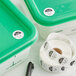 A roll of Noble Products Sunday day of the week labels on a green plastic container.
