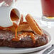 A hand pouring Heinz 57 Sauce onto a steak on a plate.