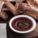 A bowl of Bull's-Eye Original BBQ Sauce next to ribs.