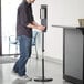 A man using a Lavex Stainless Steel automatic hand sanitizer station.