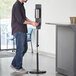 A man using a Lavex stainless steel automatic soap and sanitizer station.