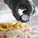 A person in black gloves using an AvaTemp digital pocket probe thermometer to check pasta temperature.