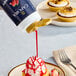 A cupcake with Capora strawberry flavoring sauce being poured onto it.