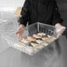 A person holding a Carlisle clear food box deep drain tray of fish.