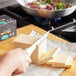 A person's hand using a knife to cut a block of Violife plant-based unsalted butter.
