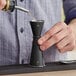 A man using a black Acopa Japanese Jigger to pour a drink.