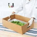 A chef using a Choice corrugated catering tray to hold spinach leaves.