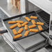 A piece of fried fish on a Baker's Mark black mesh surface.