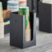 A black holder with a green cup in it.