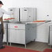 A man using an Avantco gas flat bottom fryer in a commercial kitchen.