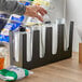 A hand reaching for plastic cups from a Choice Black countertop organizer.