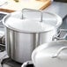 A stainless steel Vollrath pot lid on a large silver pot on a stove.