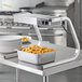 A ServIt strip warmer with "C" style legs over a metal container of french fries on a table.
