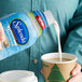 A hand pouring Splenda French Vanilla coffee creamer into a cup of coffee.