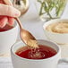 A hand holding a spoon of Sugar In The Raw over a cup of tea.