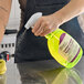 A person spraying a bottle of Noble Lemon Lance Ready-to-Use Disinfectant & Detergent Cleaner onto a countertop.