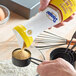 A hand pouring Domino brown sugar from a flip-top container.