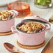 Two pink Valor Himalayan Salt enameled cast iron pots with food in them.